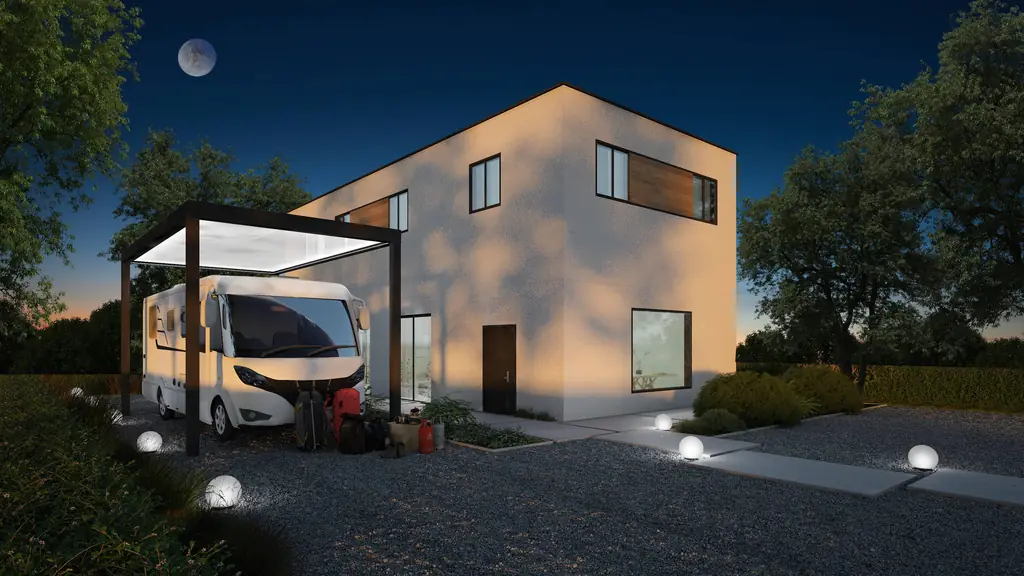 Carport autoportant abritant un camping-car, éclairé le soir